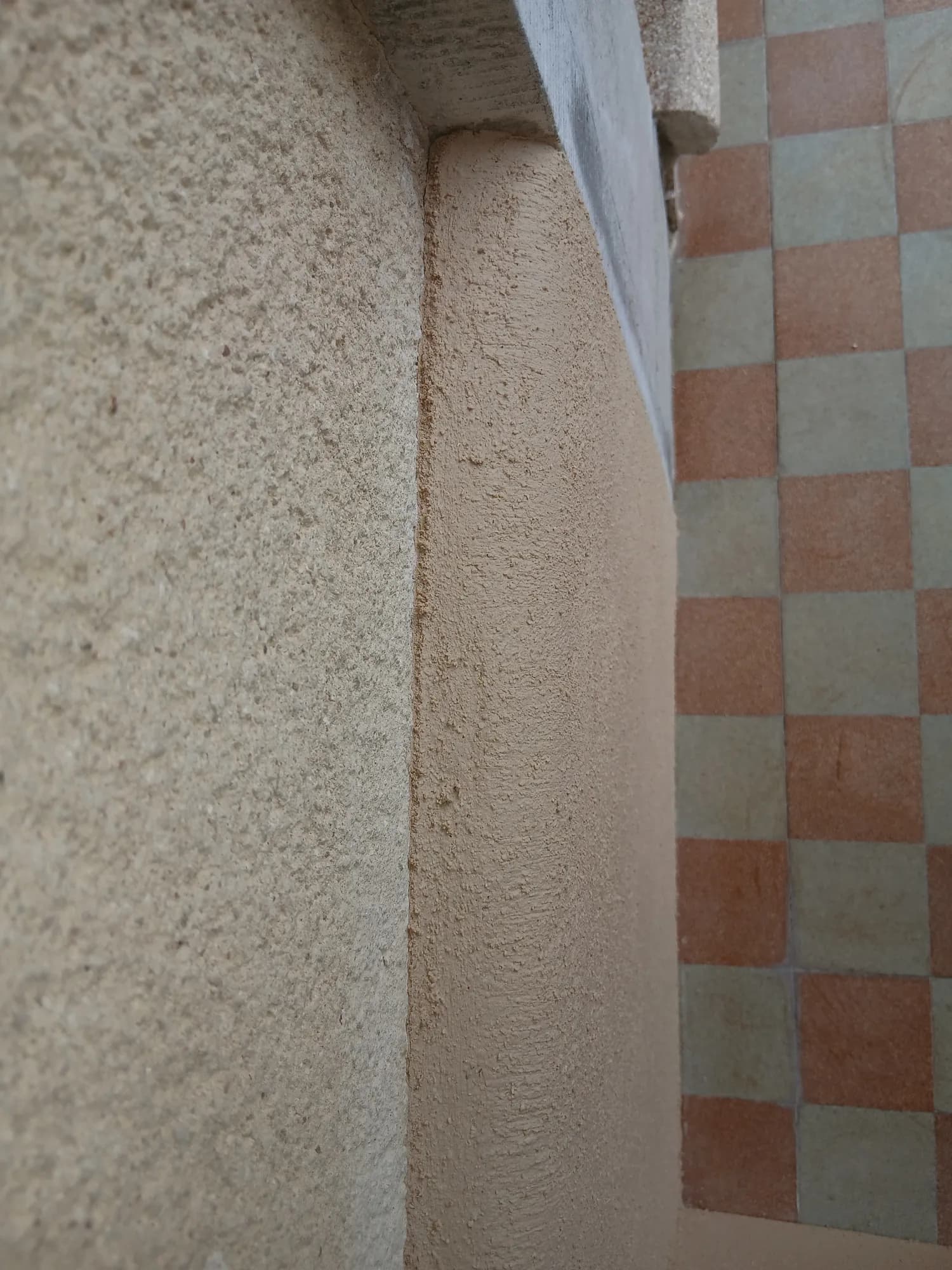 Entrée d'une maison ancienne au carrelage damier, murs et encadrements de brique enduits à la chaux