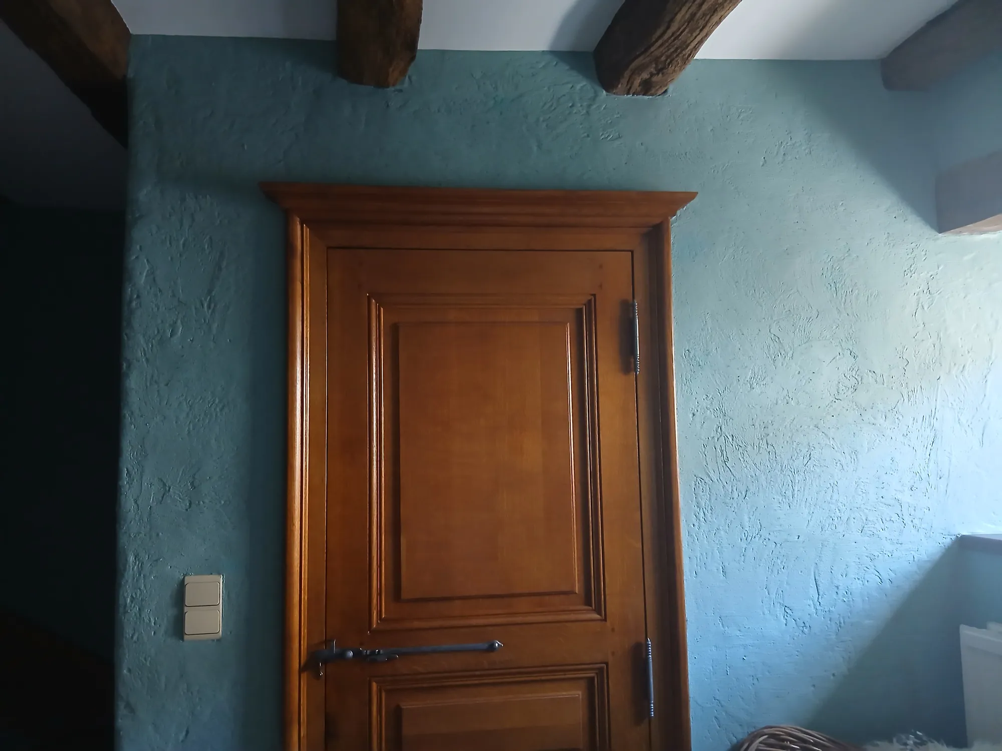 Pièce ancienne aux poutres apparentes peinte dans un bleu canard mat