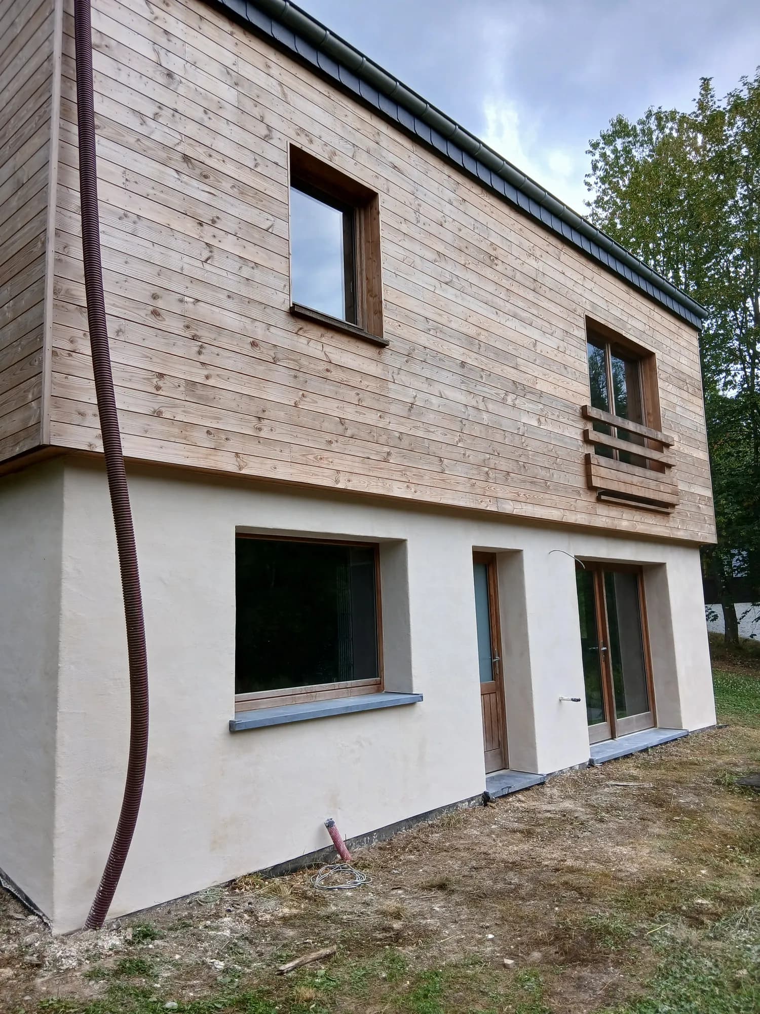 Angle de façade d'une maison ancienne enduite à la chaux, finition teinte sable